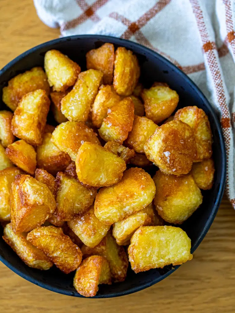 Top view of golden and crispy roast potatoes served in a bowl