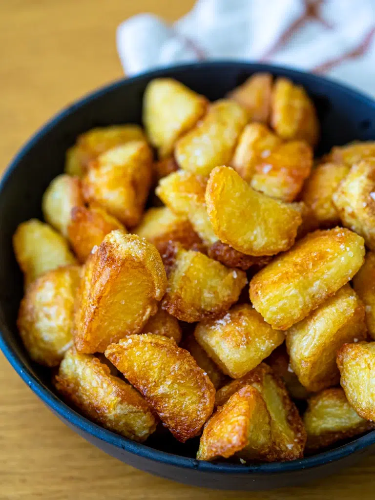 Side view of crispy golden roast potatoes served in a bowl