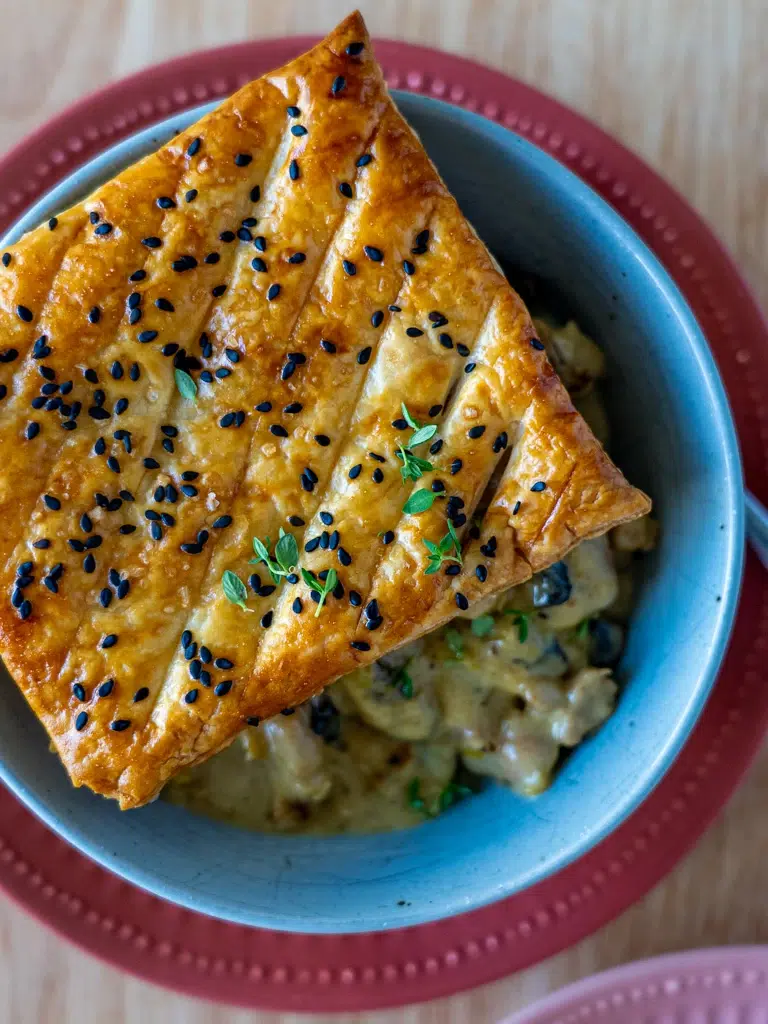 Close-up of a flaky, buttery pastry with a creamy chicken and leek filling, showcasing its golden texture.
