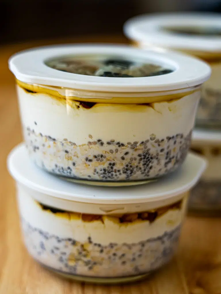 Glass jar with a secure lid containing chia and oat pudding, topped with blueberries and shredded coconut.