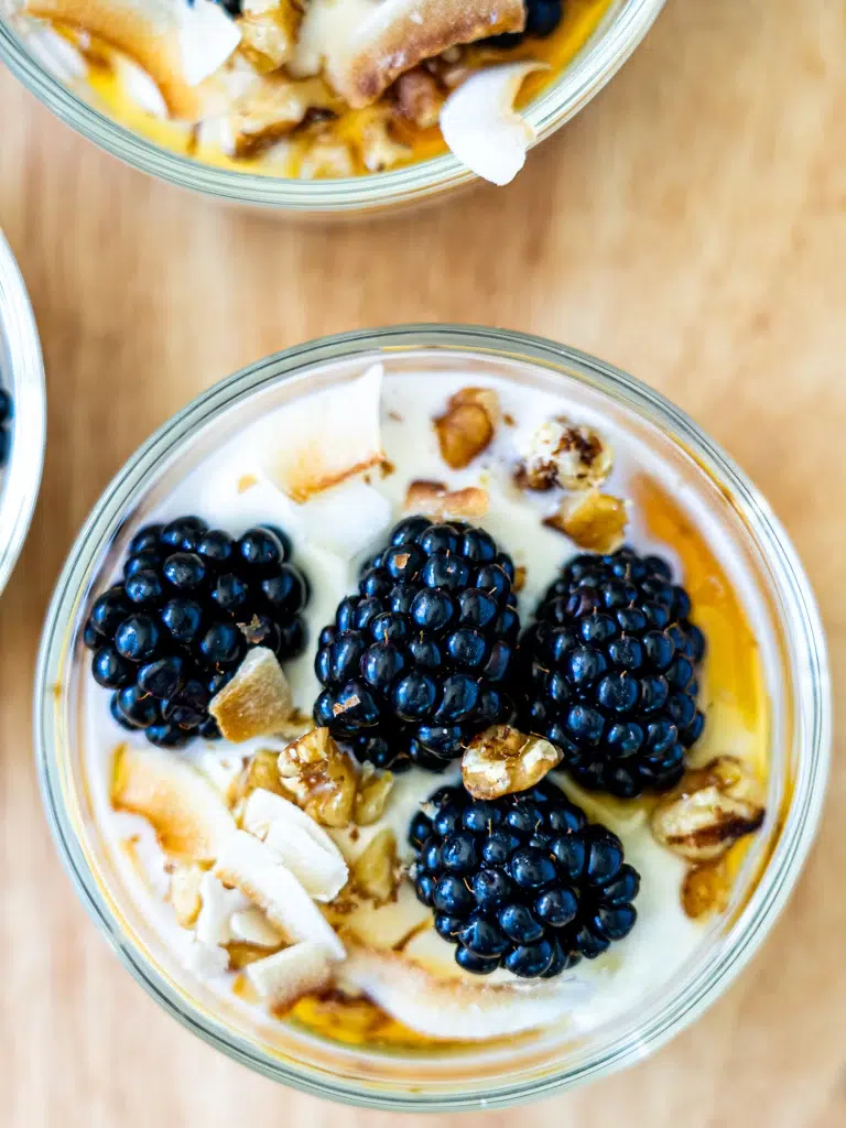 Overhead shot of chia and oat pudding in a glass jar, topped with blueberries and coconut flakes.