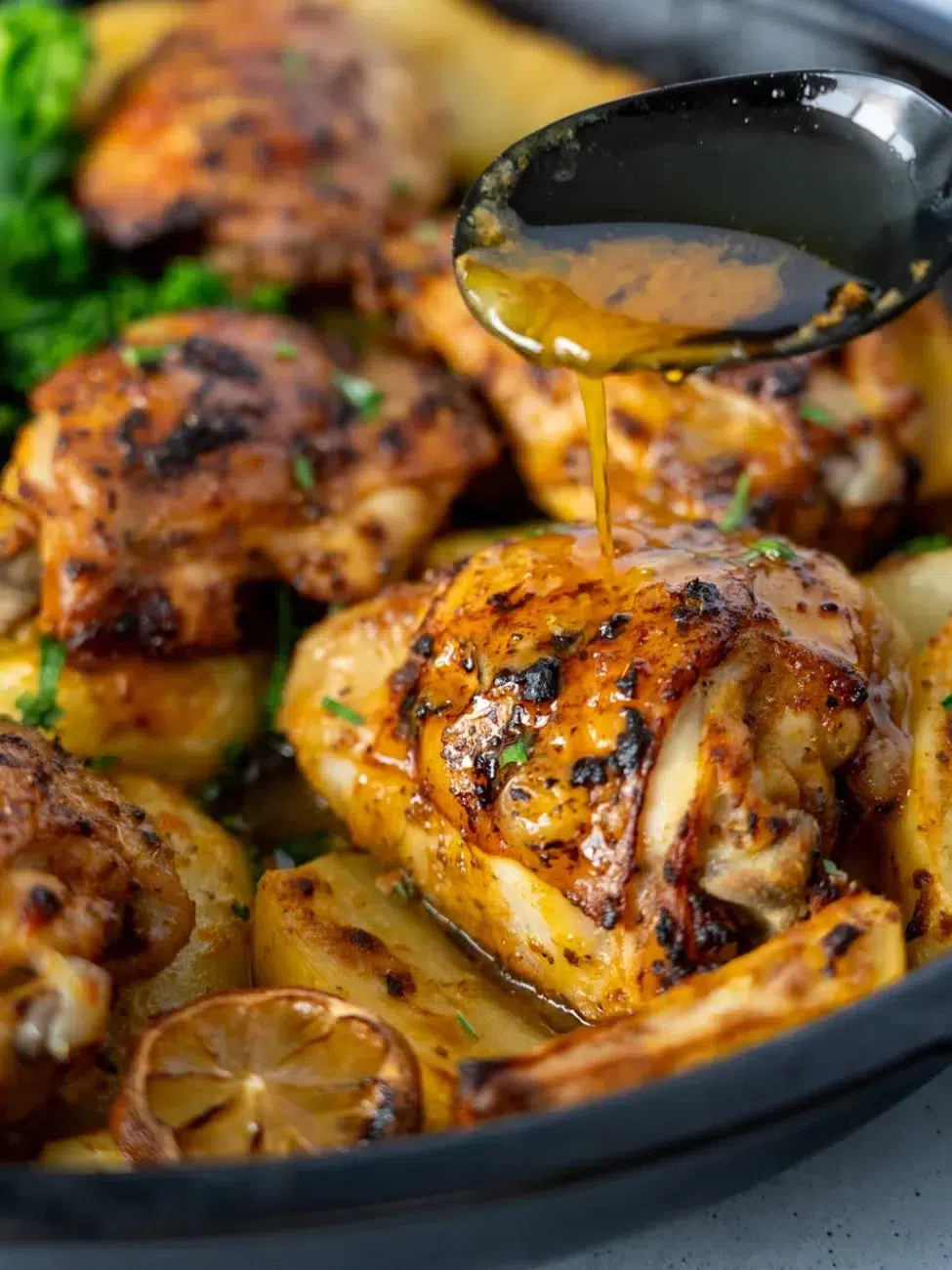 Pouring pan juices on one pan lemon garlic chicken and potatoes