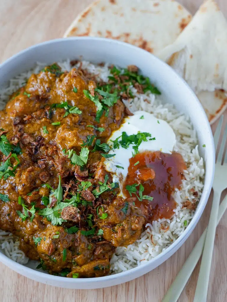 Quick coconut creamy chicken curry with tender chicken pieces, served with rice and a rich coconut sauce, garnished with fresh herbs