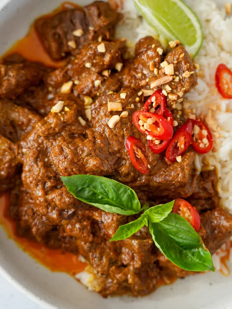 Close-up of Coconut Beef Curry in a bowl with a garnish of fresh herbs.