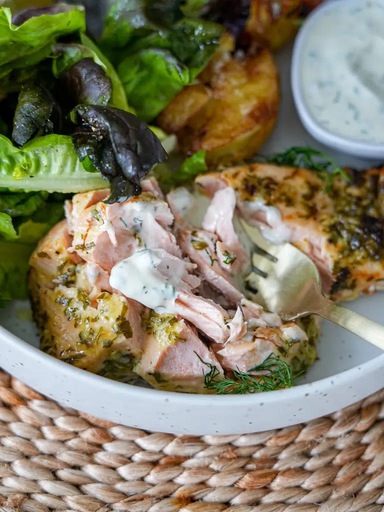 Dijon salmon on a serving plate, cooked to flaky perfection, alongside crispy potatoes, fresh herbs, lemon, and dipping sauce