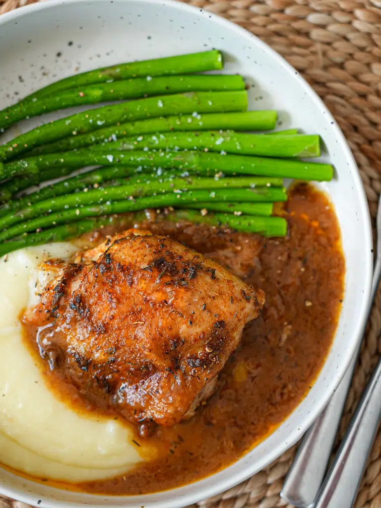 Hearty baked chicken with gravy served with greens and mashed potatoes
