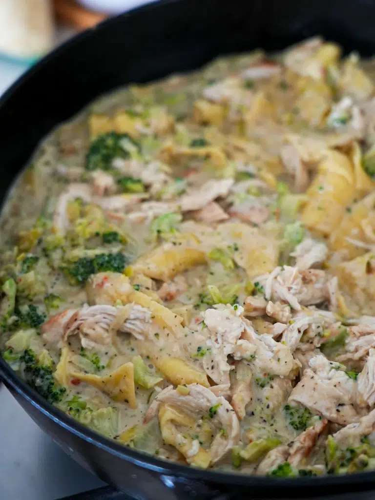 Side view of unbaked Chicken and Broccoli Lasagne in a pan, with creamy white sauce and spinach layers waiting to be topped.