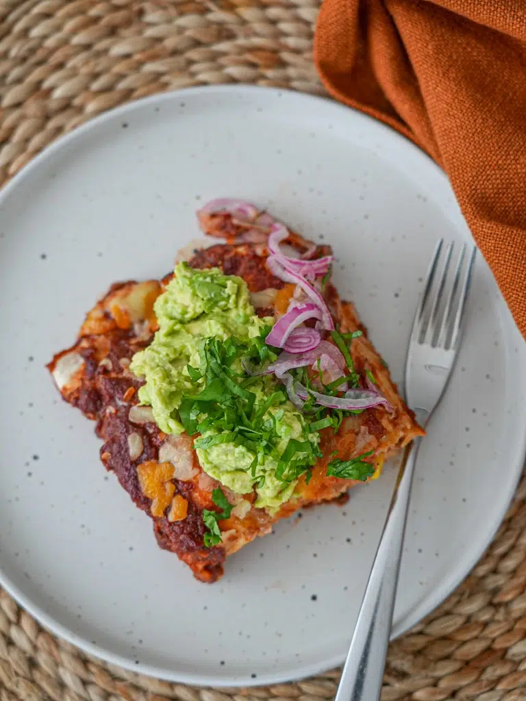 Plate of cheesy chicken enchilada topped with fresh garnishes