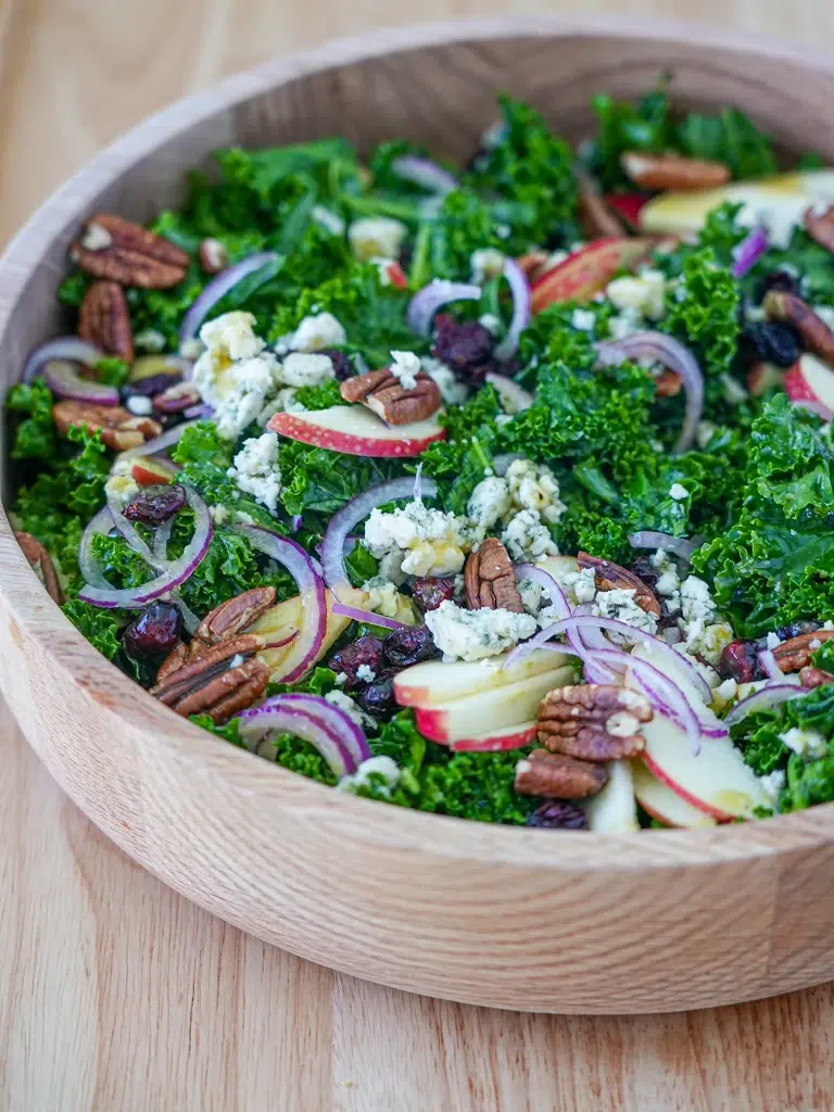 Side view of a bowl of maple kale salad with dried cranberries and blue cheese.