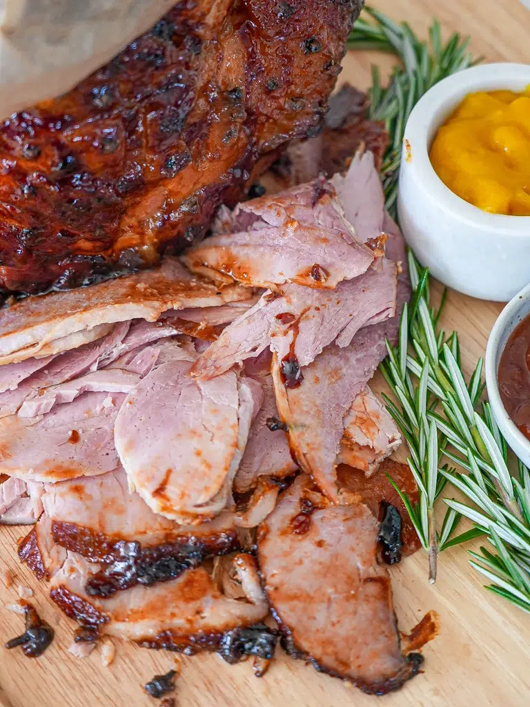 Carved glazed ham on a wooden board, showcasing juicy slices and a rich glaze.