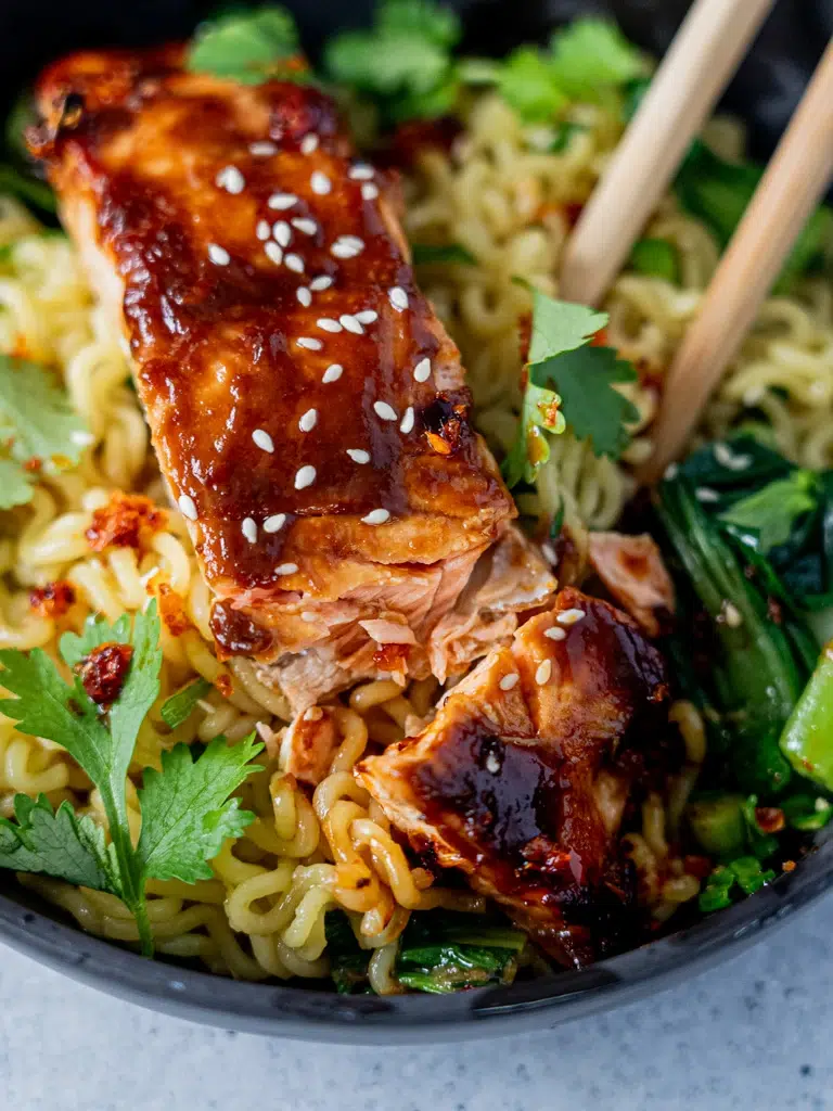Close-up of tender miso salmon fillet atop ramen noodles, highlighting its rich color and texture.
