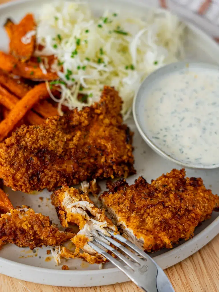 Close-up of Southern baked chicken strips with a fork in the chicken, ready to eat.