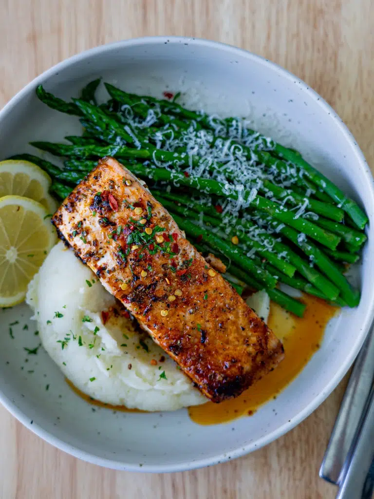 Overhead view of baked lemon butter salmon plated with asparagus and mashed potatoes.