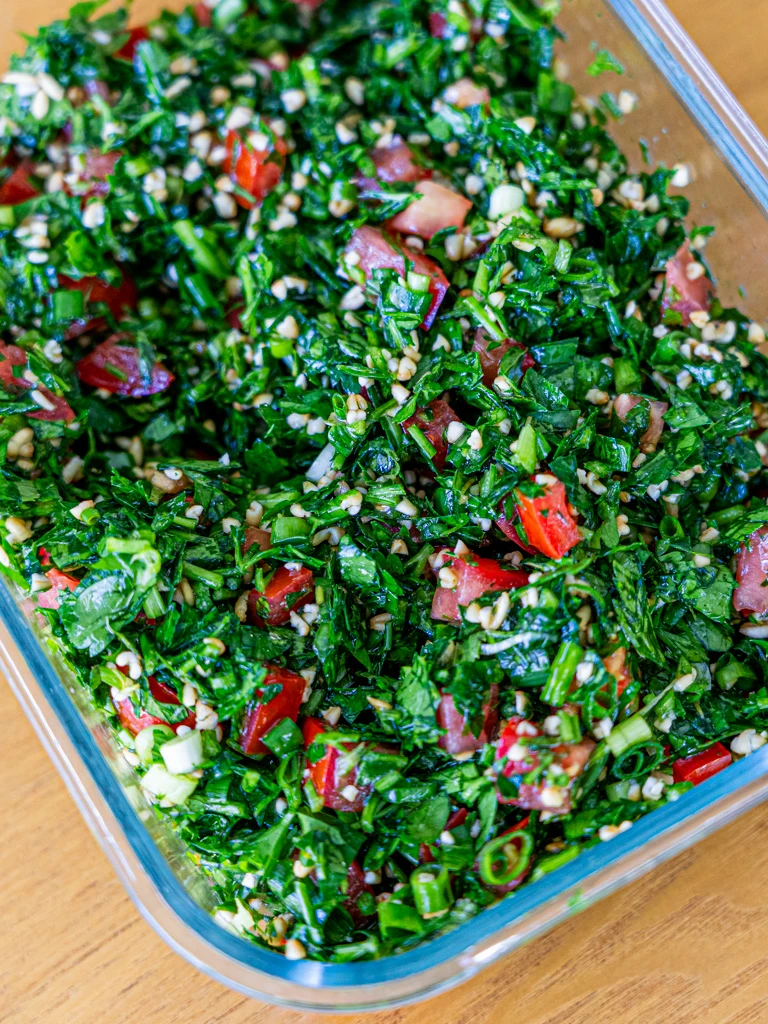 Fresh tabouli salad with parsley, tomatoes, and bulgur stored in an airtight container.