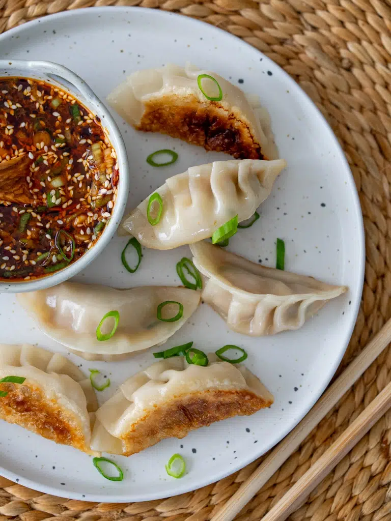 Sideways-plated Dumpling Dipping Sauce with chopsticks placed beside the dish.