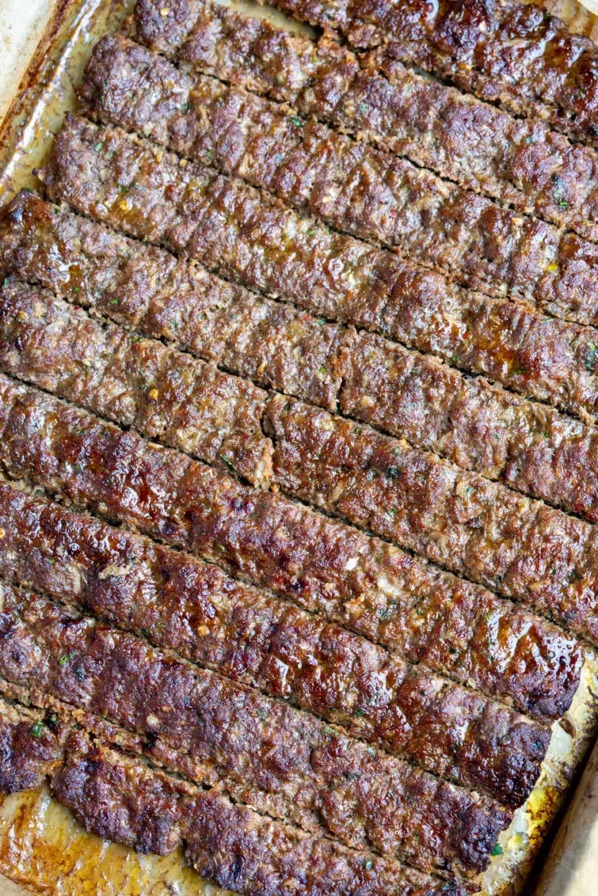 Tray of cooked beef kebabs, and juicy, freshly baked and still in the parchment-lined tray