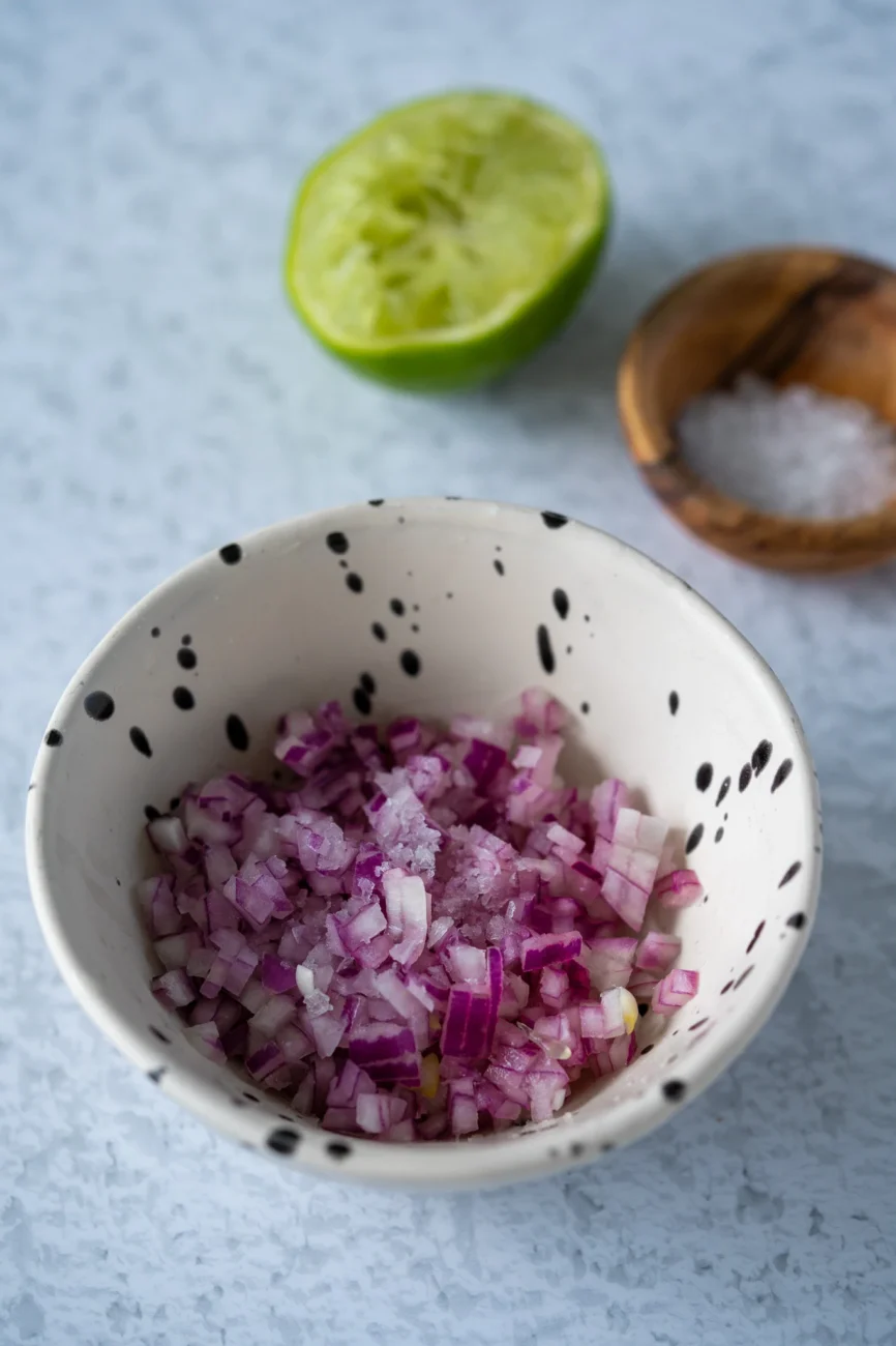 Red Spanish onion in a small bowl with fresh lime on the side for guacamole recipe