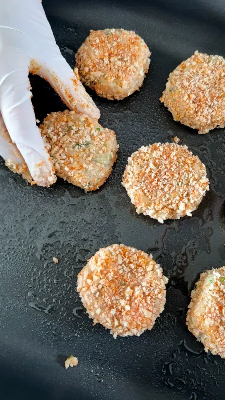 chicken rissoles going onto an oil sprayed baking tray