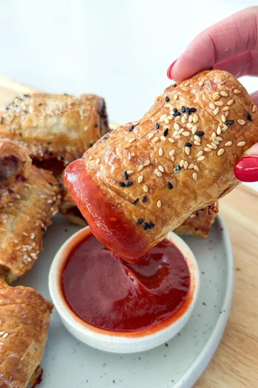 homemade sausage roll being dipped into ketchup