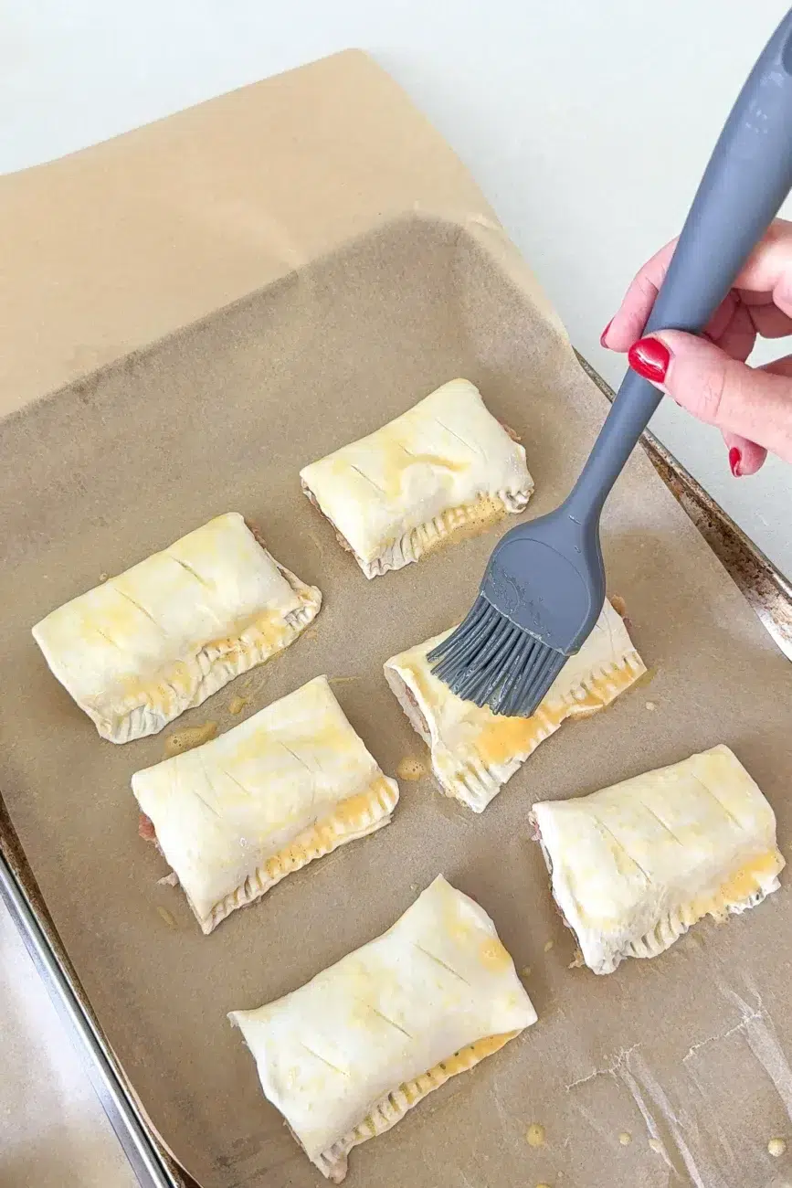 sausage rolls being brushed with egg wash