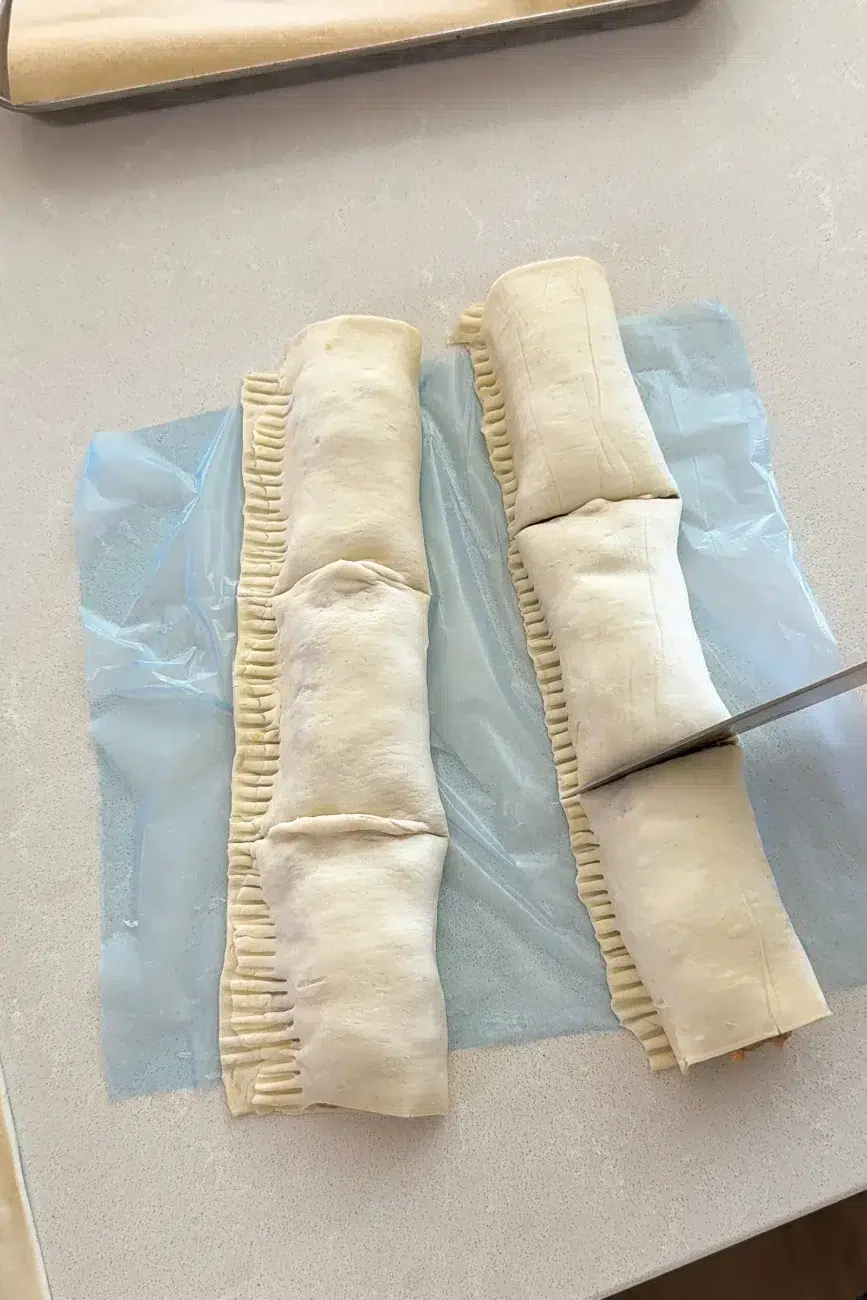 sausage rolls being cut with knife into three