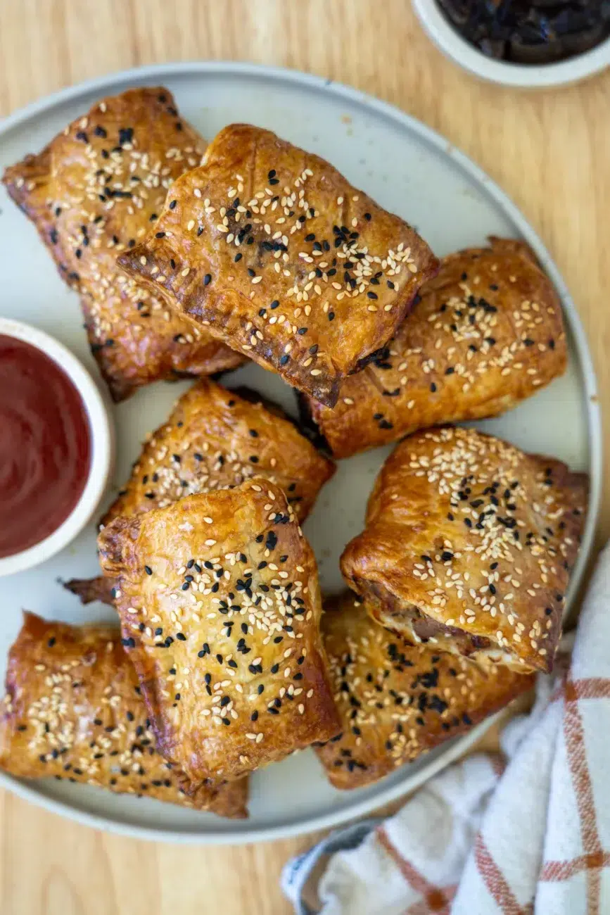 sausage rolls plated with ketchup and onion relish on side