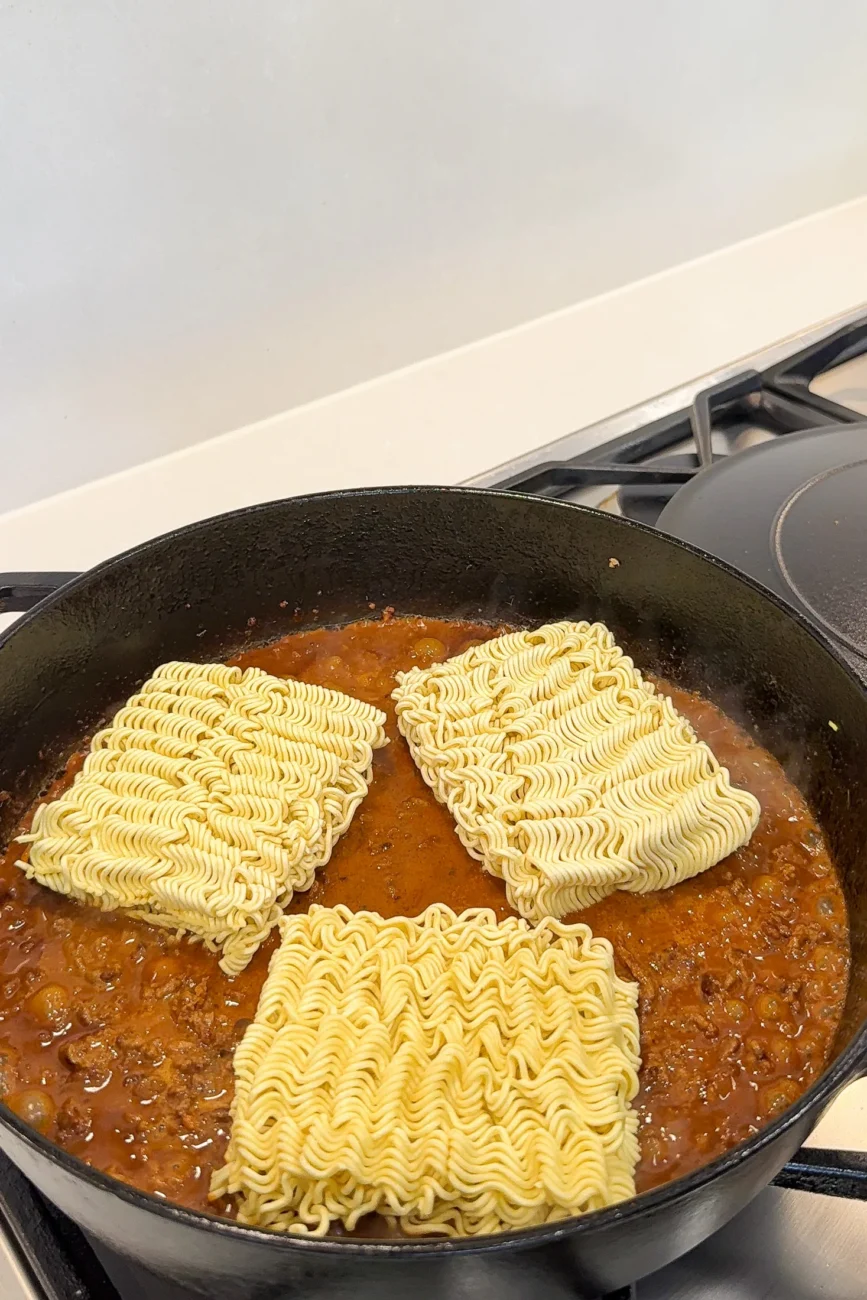 Nestle the ramen noodle blocks into the sauce and don't worry if they're not fully submerged. Pop the lid on and the steam will soften them perfectly.