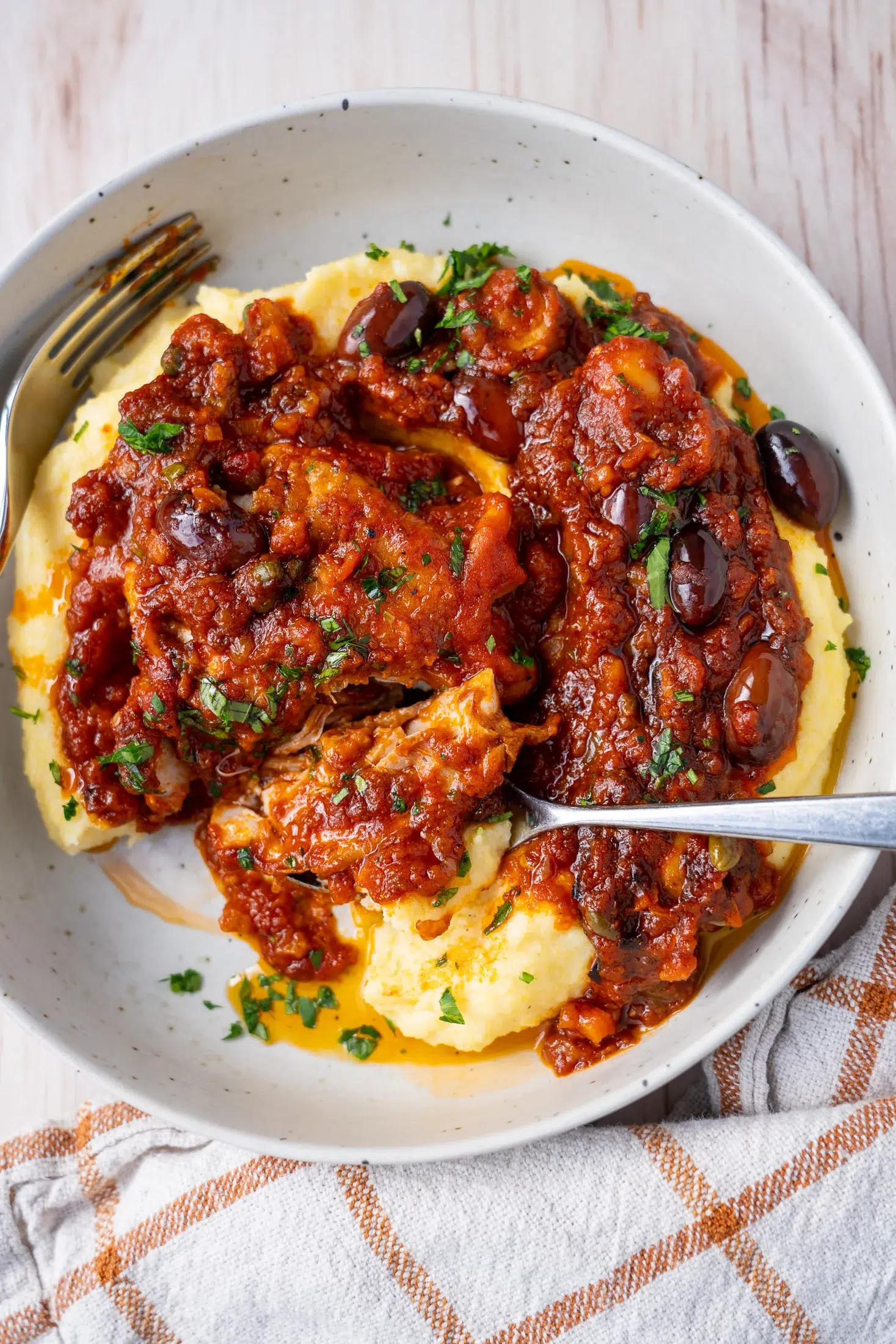 Chicken cacciatore with tomato sauce spooned over creamy parmesan polenta