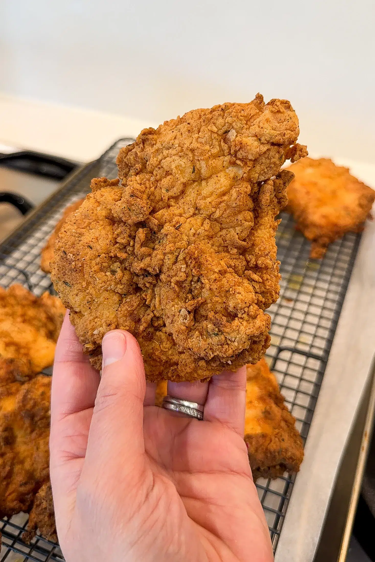 Crispy fried chicken pieces resting on a wire rack after cooking