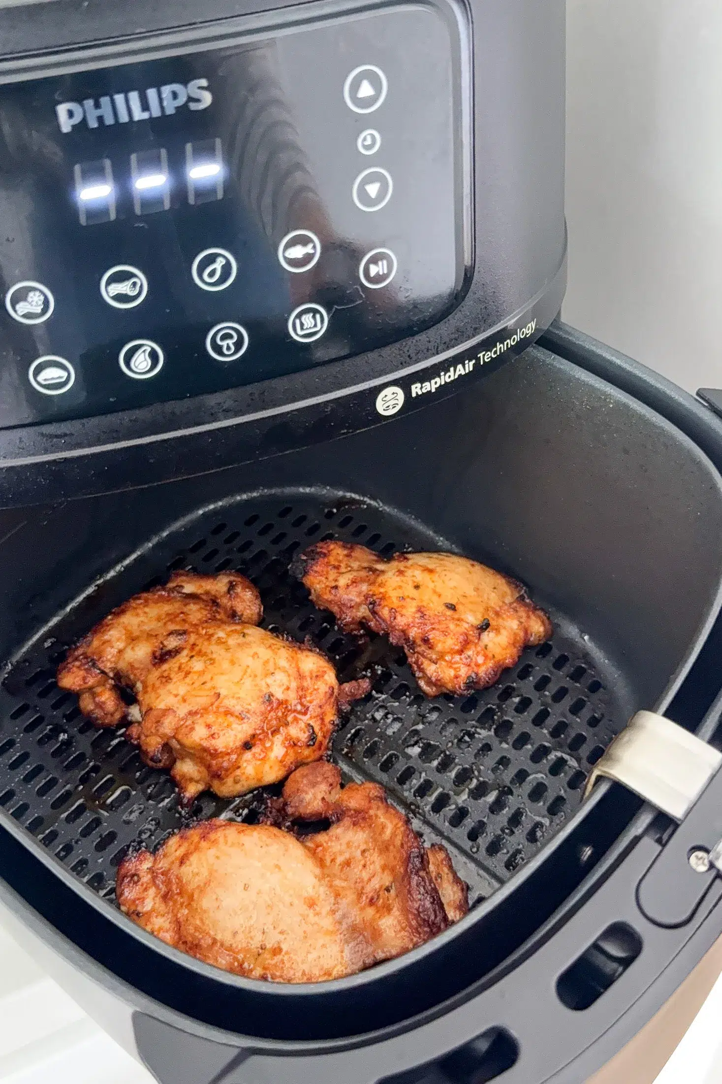 Golden crispy chicken thighs in a Philips air fryer basket