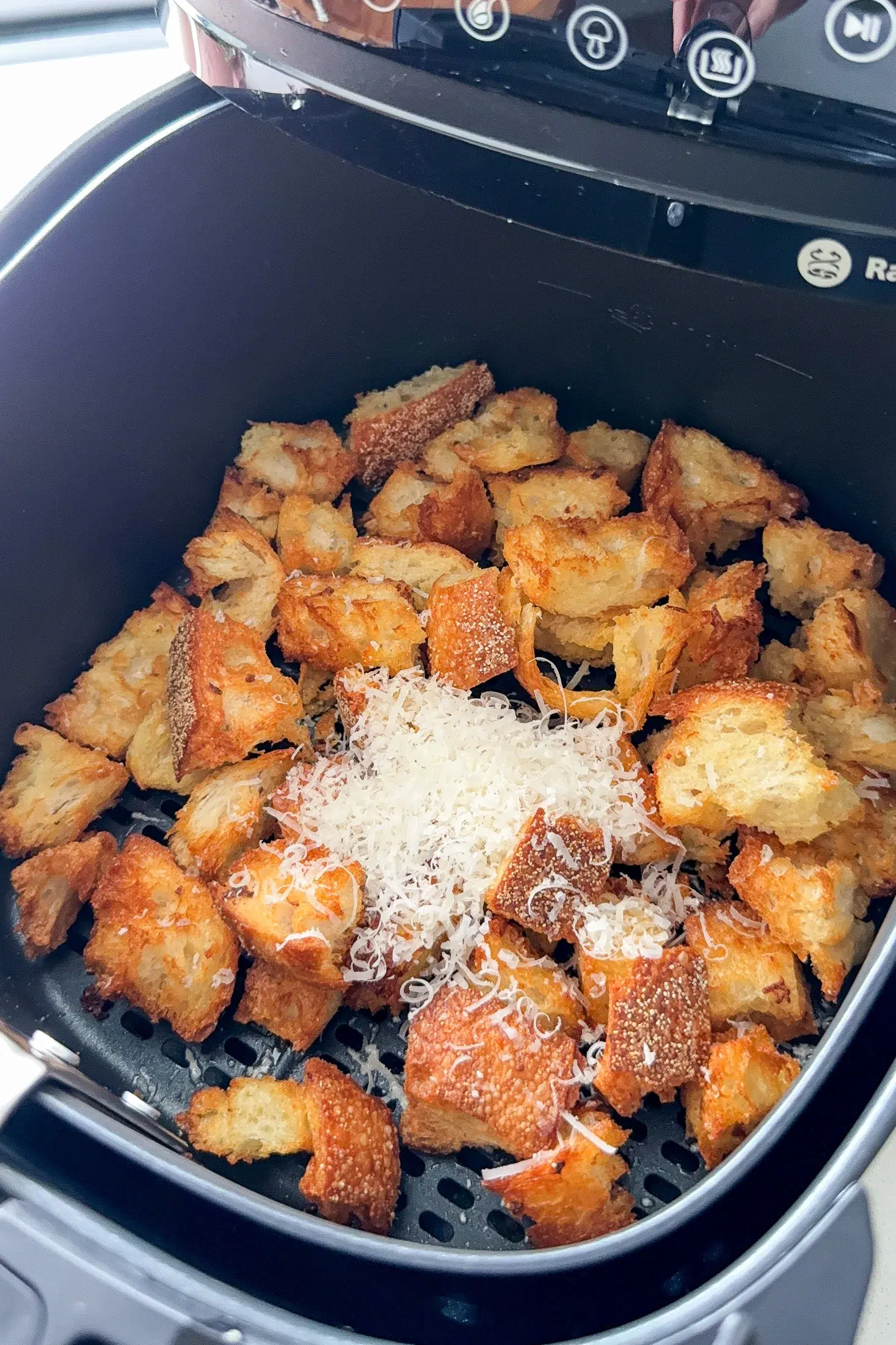 Garlic parmesan croutons cooking in an air fryer basket