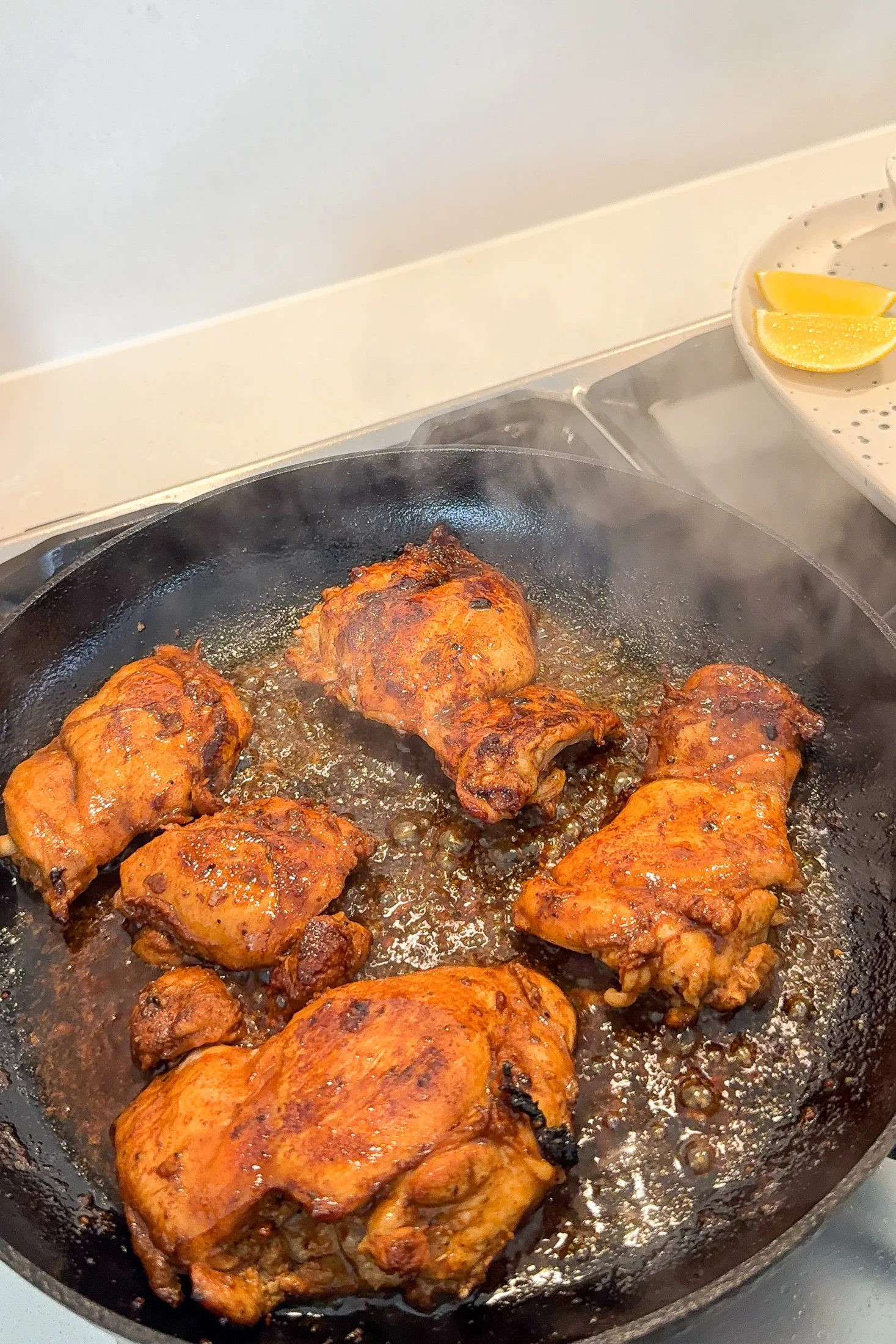 Chicken thighs cooking in a cast iron skillet with golden-brown caramelised edges