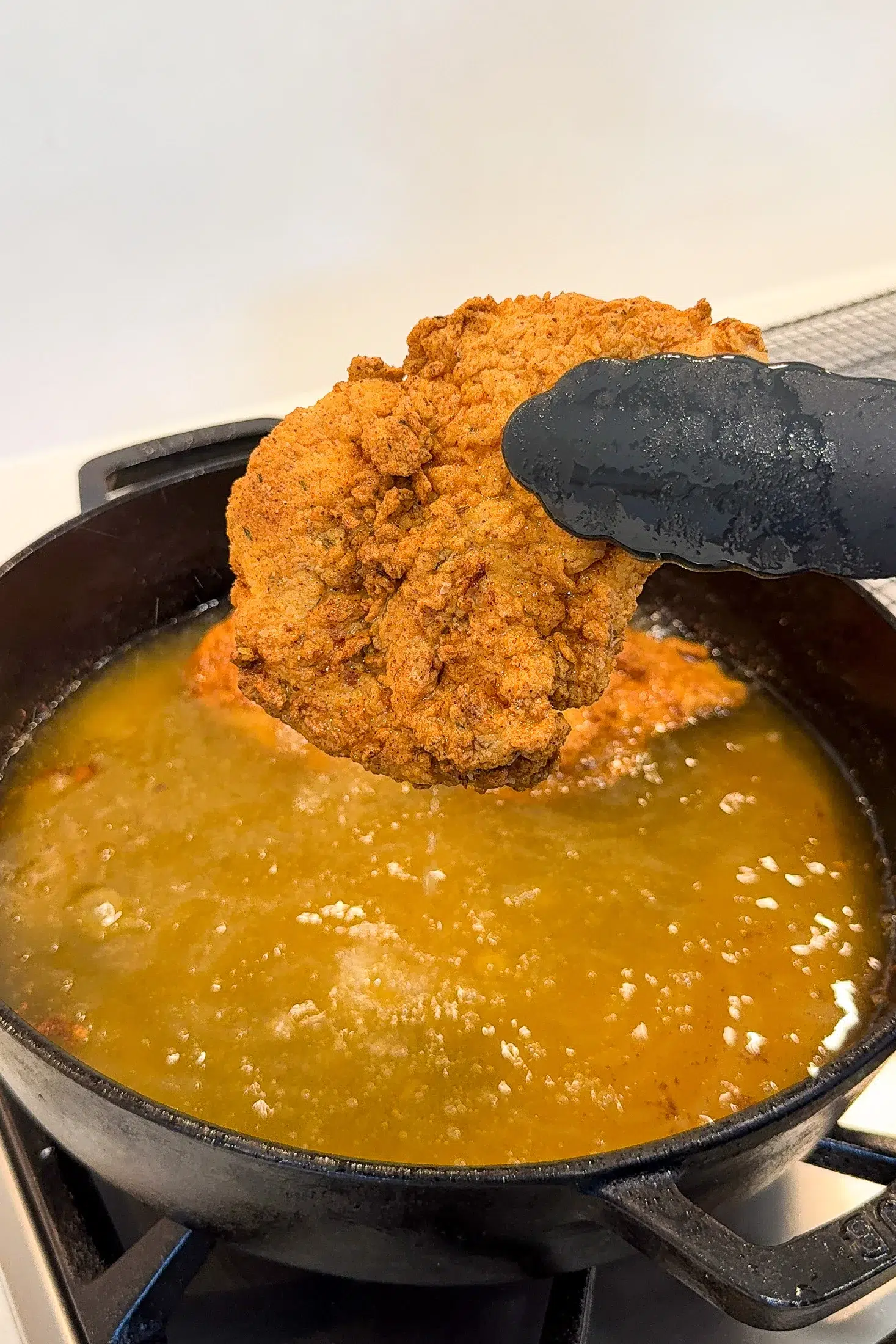 Golden crispy fried chicken cooking in oil in a saucepan