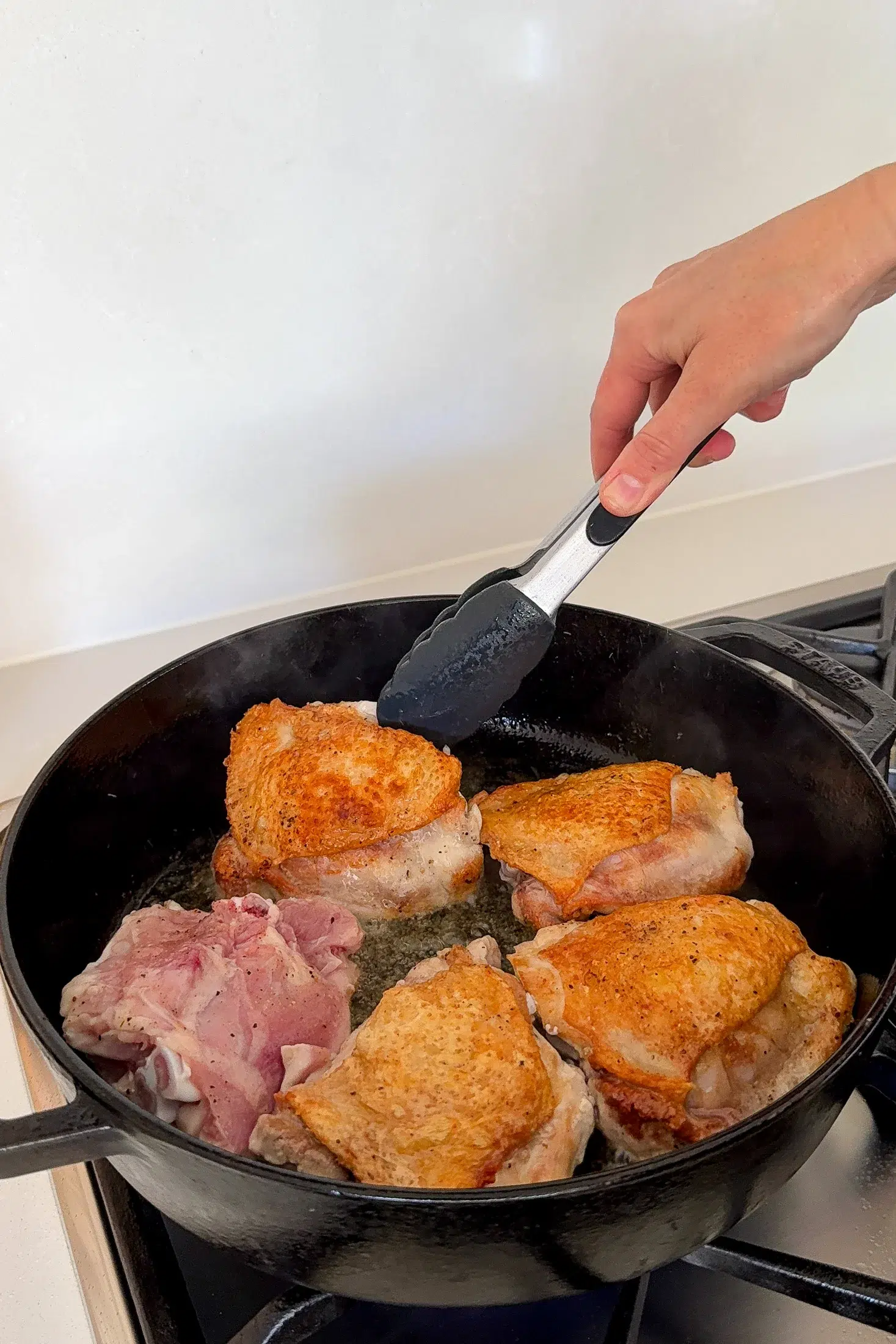 Searing bone-in chicken thighs skin-side down in a cast iron skillet