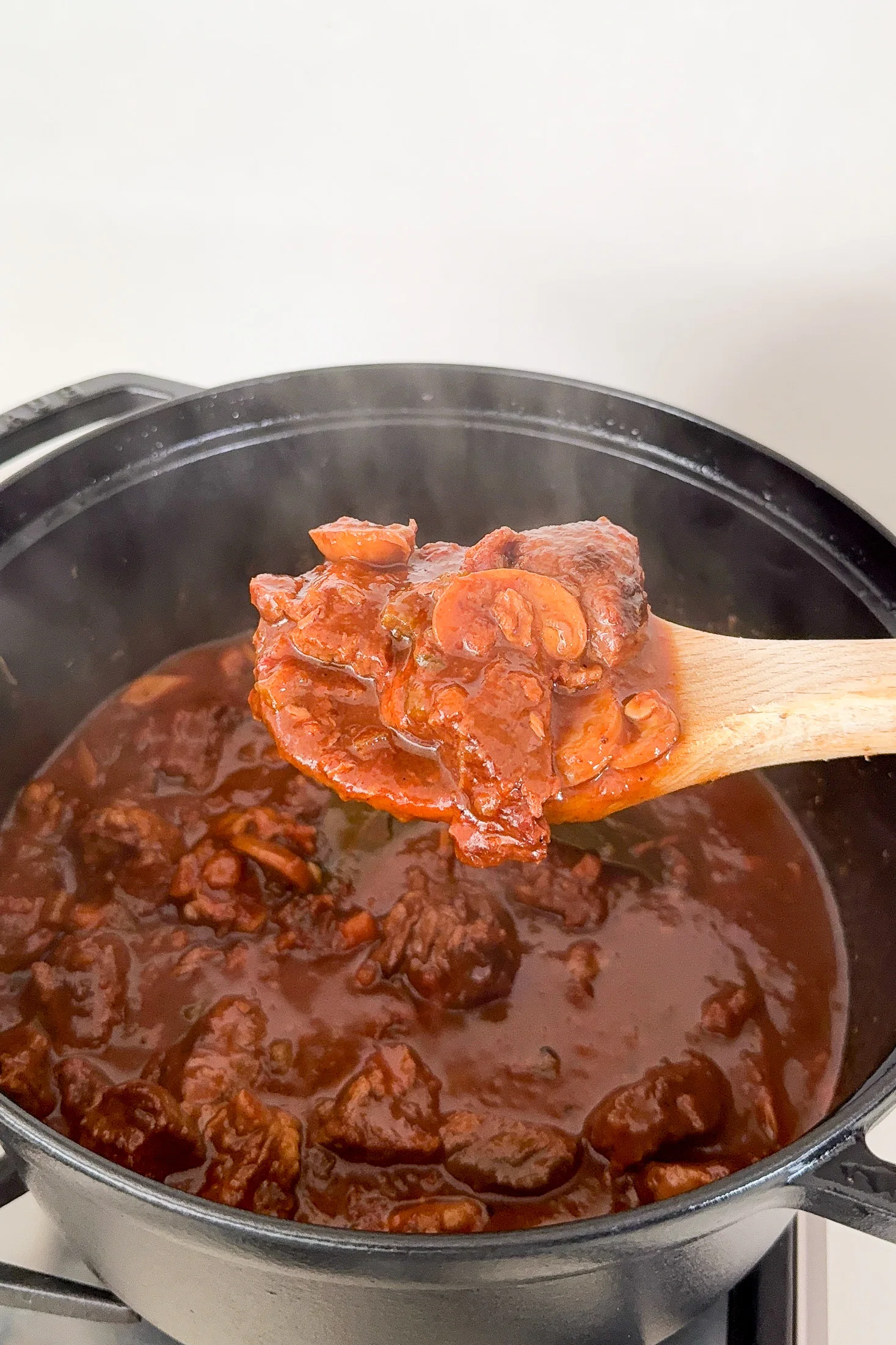 Thick and glossy slow-cooked beef ragu on a spoon