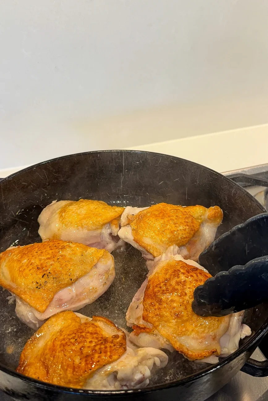 Chicken thighs seared in pan until golden
