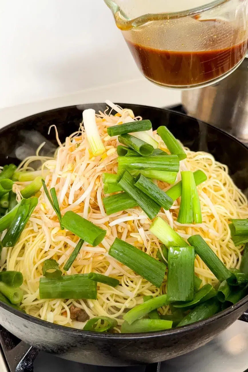 Noodles beansprouts and spring onion added to pan