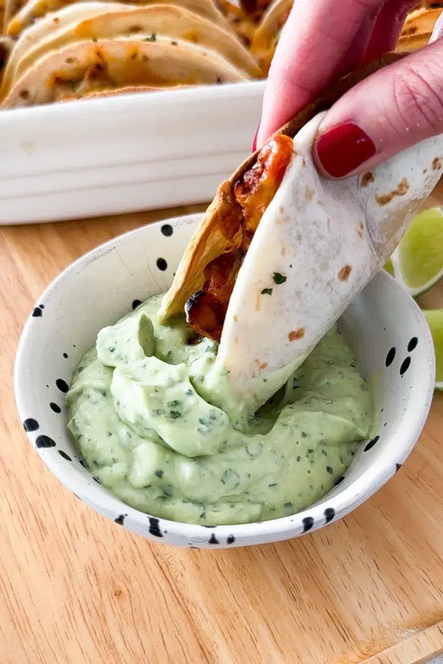 Taco being dipped in avocado cream