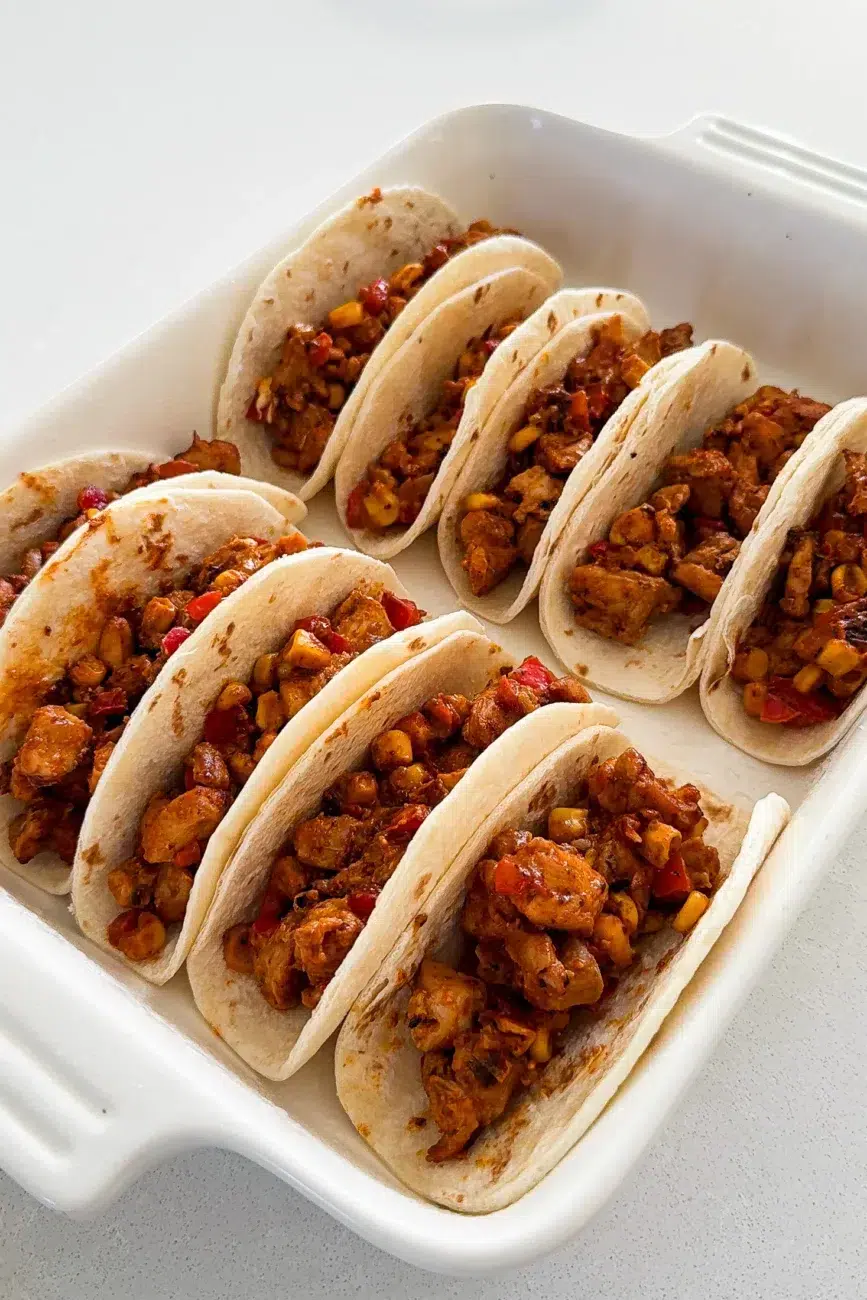Tacos filled and ready for cheese and assembled in baking tray